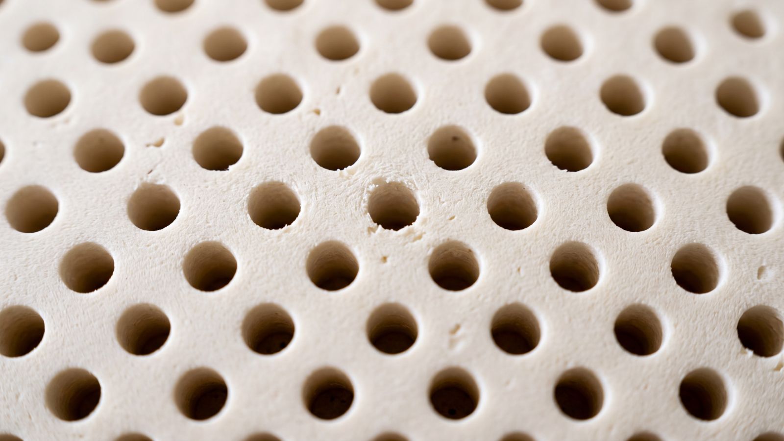 Primer plano de una plancha de látex natural con sus perforaciones de ventilación